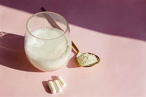 Pohár s kolagénovým nápojom a kapsule s biotínom a vitamínmi