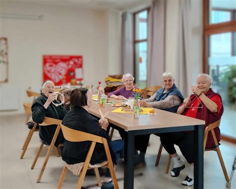 Skupina seniorov pri reminiscenčnej terapii, kde si prezerajú staré fotografie