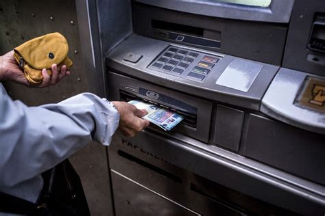 Dôchodca vyberajúci hotovosť z bankomatu