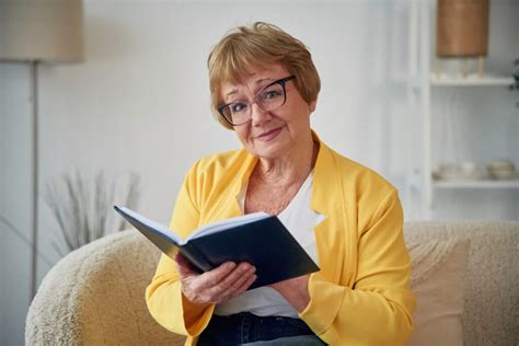 Imobilný senior čítajúci knihu s opatrovateľkou