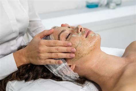 Detail rúk aplikujúcich peeling na ženskú tvár
