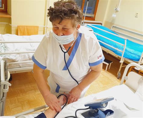 Sestrička umývajúca vlasy ležiacej pacientky pomocou špeciálneho umývadla