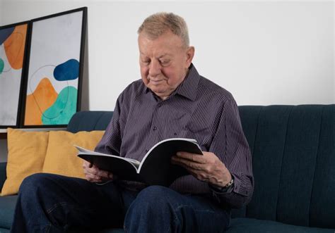 Nemobilný senior čítajúci knihu, zatiaľ čo sedí v kresle.