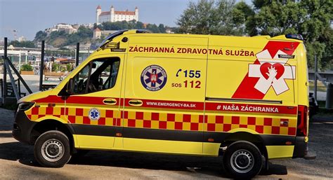 Sanitka s logom DZS a personálom pomáhajúcim pacientovi