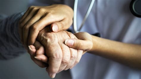Opatrovateľka drží ruku seniorky, symbol empatie a komunikácie
