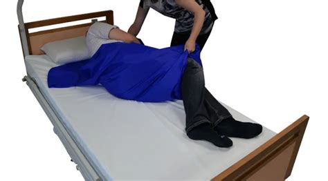 Opatrovateľka vykonávajúca hygienu ležiaceho pacienta na lôžku