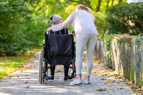 Opatrovateľka pomáhajúca seniorovi s chôdzou