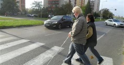 Zrakovo postihnutá osoba s bielou palicou prechádza cez ulicu