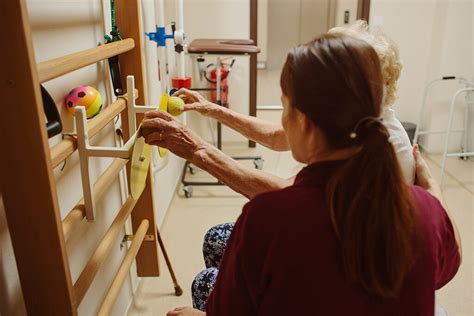 Fyzioterapeut cvičiaci so seniorom v rehabilitačnej miestnosti