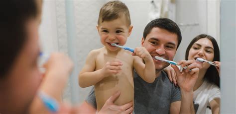 Rodič čistí zuby dieťaťu v polohe poležiačky