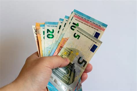 Pacient držiaci v ruke krabičku liekov a bankovky, symbolizujúce finančnú pomoc.