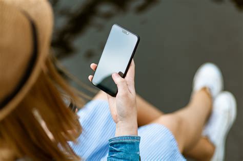 Človek s mobilom v ruke a reťazou okolo zápästia symbolizujúcou závislosť