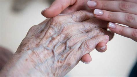 Žena držiaca ruky seniorky