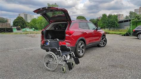 Ilustrácia osoby s invalidným vozíkom nastupujúcej do prispôsobeného automobilu