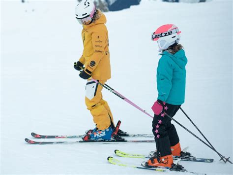 Dieťa lyžujúce s lyžiarskym popruhom a inštruktorom