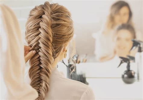 Žena si robí francúzsky vrkoč pred zrkadlom
