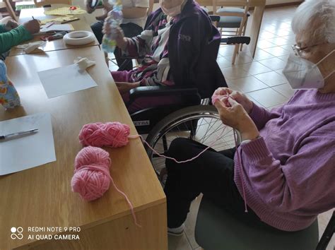 Skupina usmievajúcich sa seniorov spoločne tvorí ručné práce
