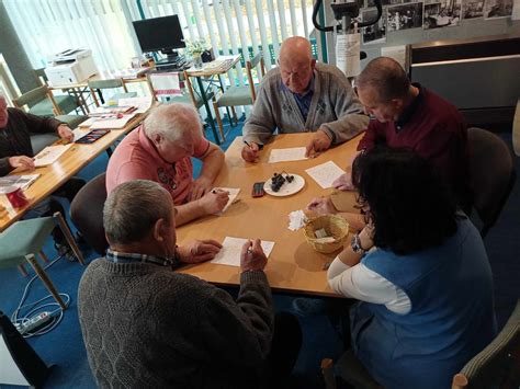 Skupina seniorov usmievajúcich sa a zapojených do aktivity v dennom stacionári.